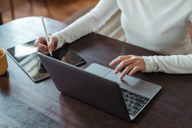A person at a desk, using their laptop working on the format of their press release